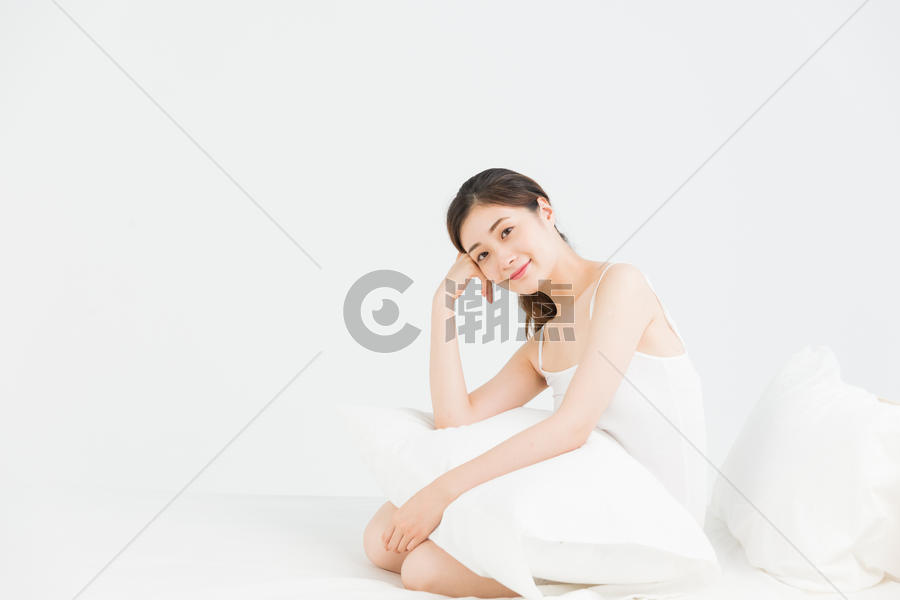 年轻女性床上抱着枕头放松图片素材免费下载