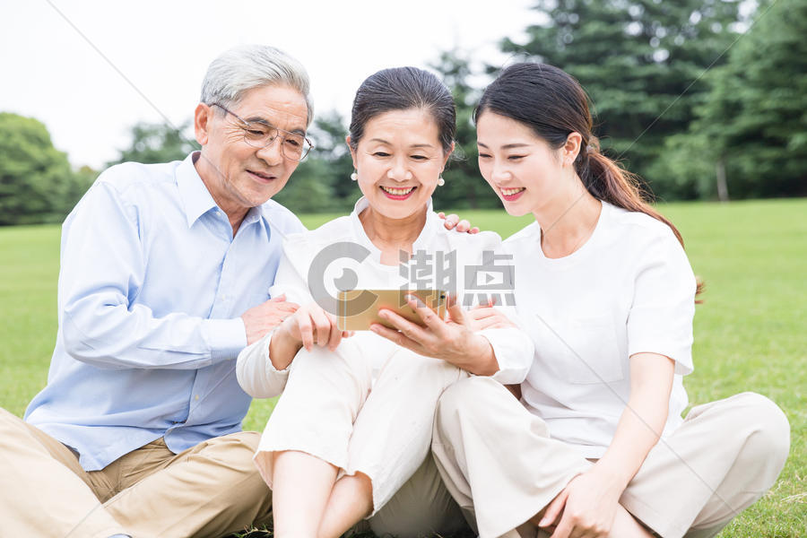 草地上幸福一家人看手机图片素材免费下载