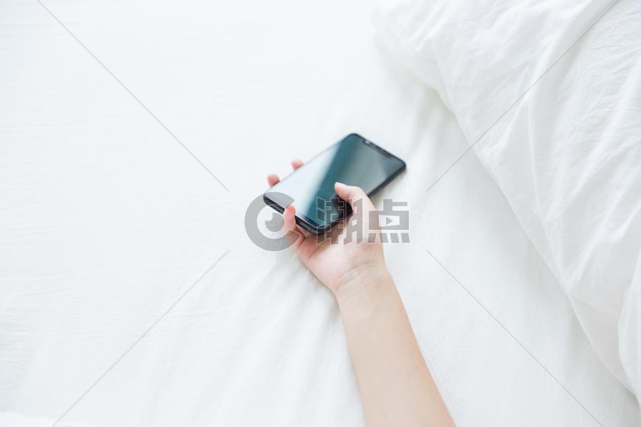 床上女性手拿手机特写图片素材免费下载