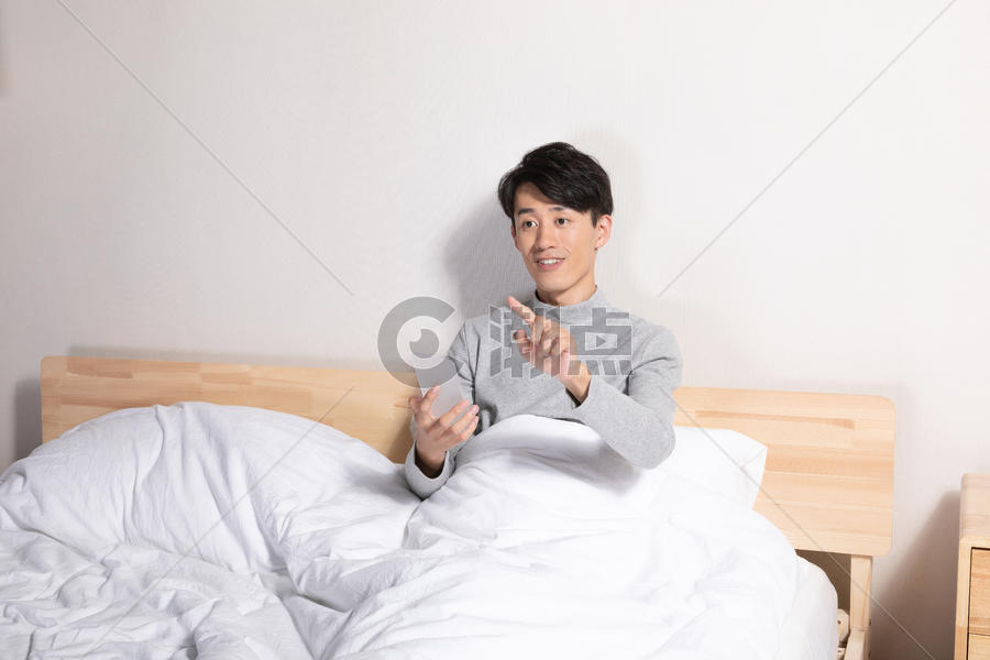 躺在床上玩手机的男性图片素材免费下载