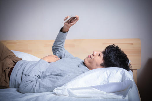 躺在枕头上玩手机的男人图片素材免费下载