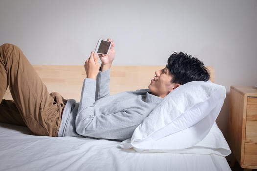 躺在枕头上玩手机的男人图片素材免费下载