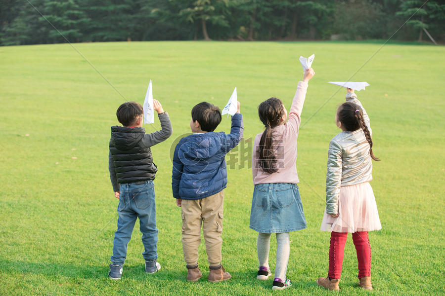 草地上玩纸飞机的孩子们图片素材免费下载