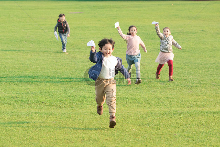 草地上玩纸飞机的孩子们图片素材免费下载