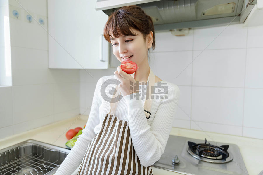 厨房里吃番茄的家庭主妇图片素材免费下载