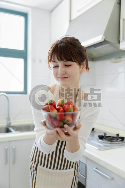 厨房里吃草莓的年轻女性图片素材免费下载