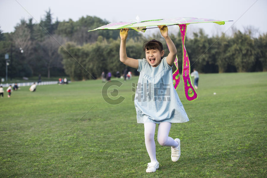 小女孩拿着风筝在草坪上奔跑图片素材免费下载