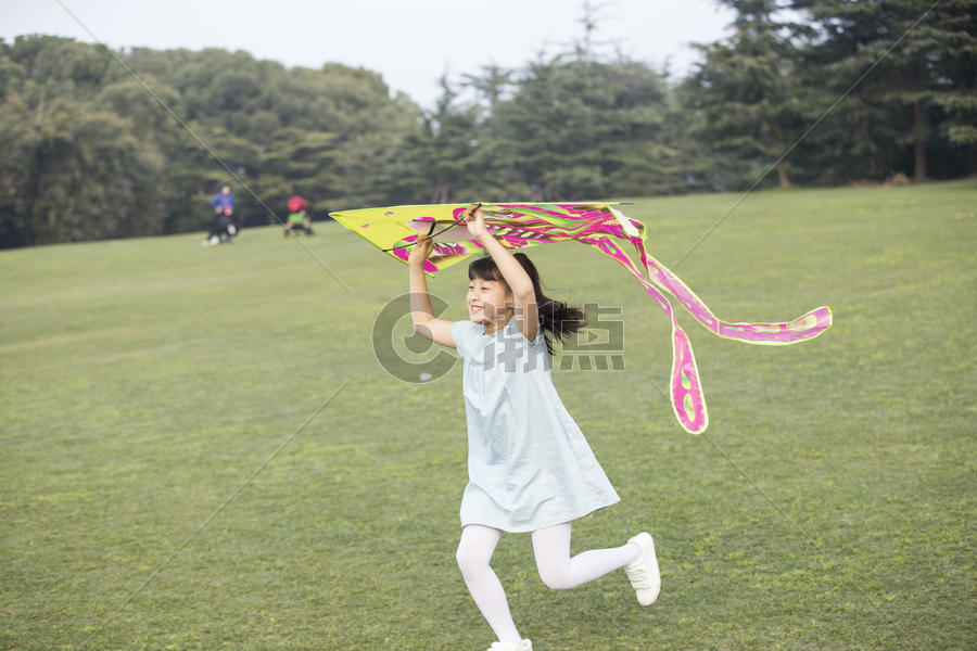 小女孩拿着风筝在草坪上奔跑图片素材免费下载