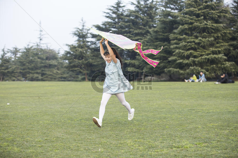 小女孩拿着风筝在草坪上奔跑图片素材免费下载