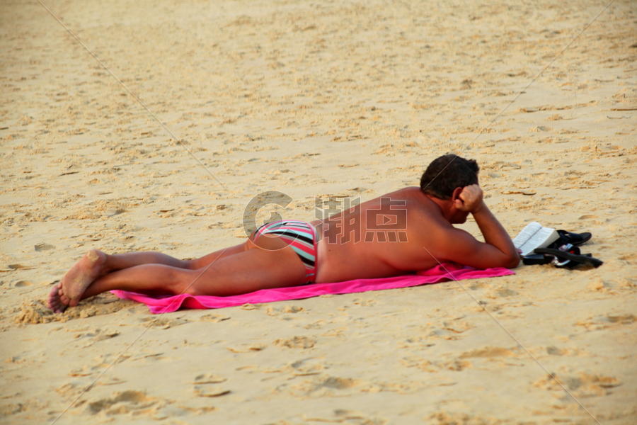 俯卧在沙滩上看书的男人图片素材免费下载