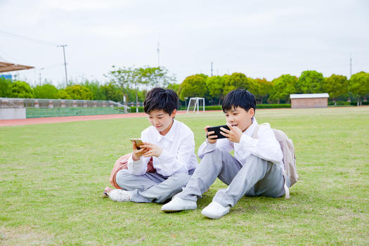 小学生操场玩手机图片素材免费下载