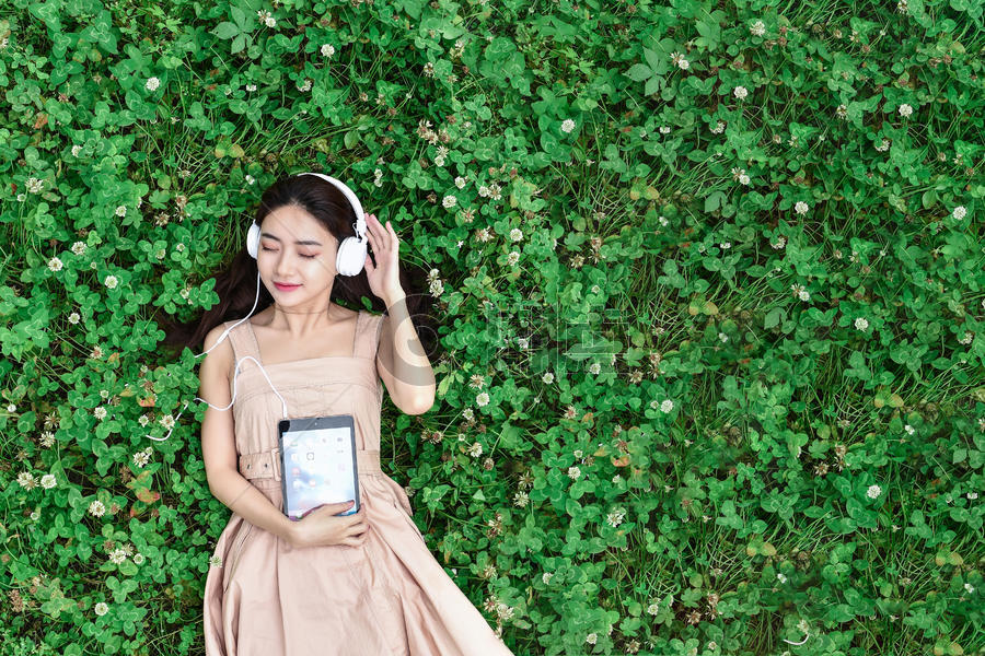 草坪戴耳机玩平板的女生图片素材免费下载