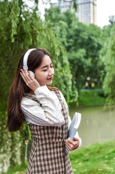公园带耳机看书的女学生图片素材免费下载