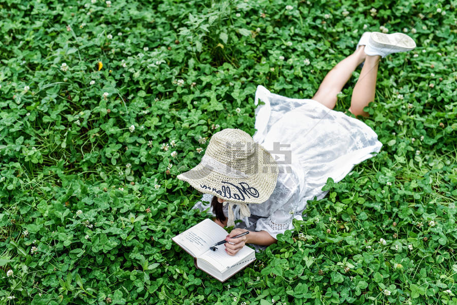 草坪上趴着看书的美女图片素材免费下载