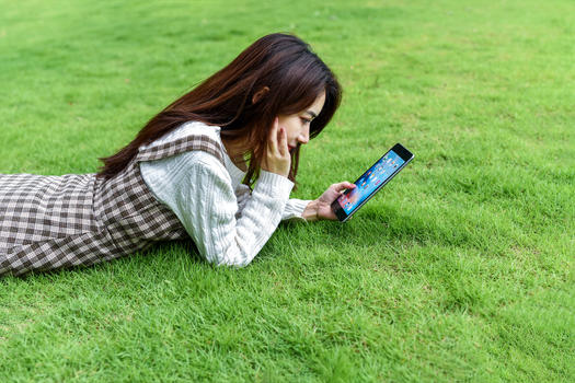 草坪上玩平板的女生图片素材免费下载