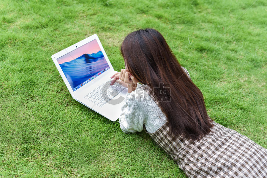 趴在草地玩电脑的女孩图片素材免费下载