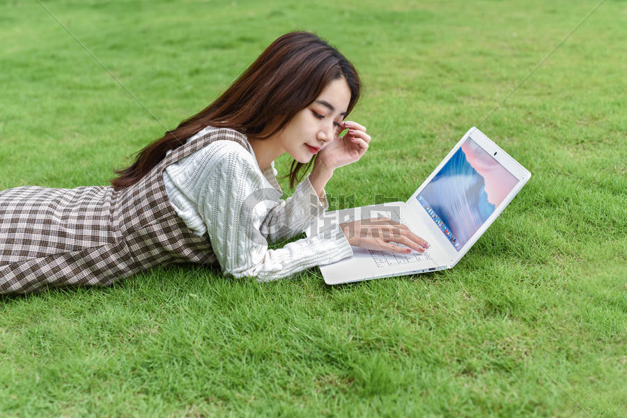 草地上玩电脑的女生图片素材免费下载