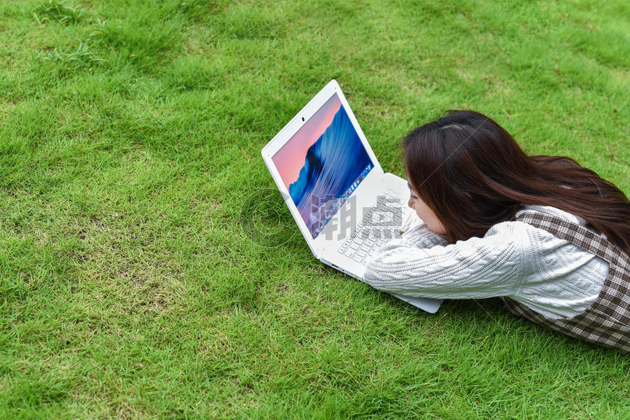草坪上趴着玩电脑的女生图片素材免费下载
