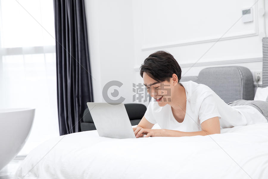 男青年卧室床上用电脑图片素材免费下载