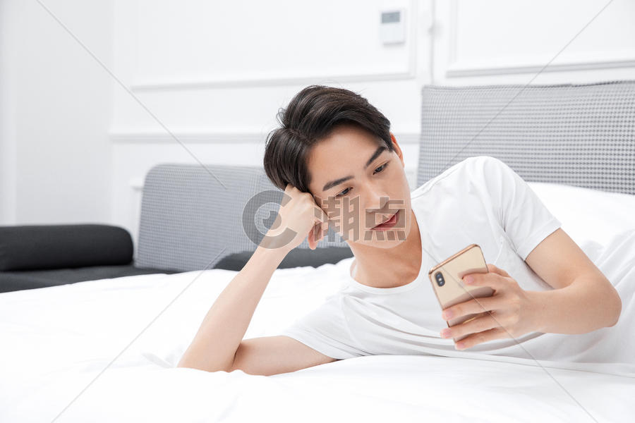 男青年卧室床上用手机图片素材免费下载