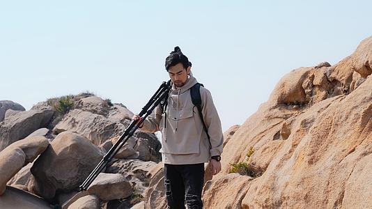 风光摄影师扛着相机登山视频的预览图