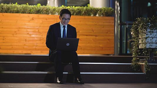 4k夜景商务男性坐在台阶上使用笔记本电脑视频的预览图