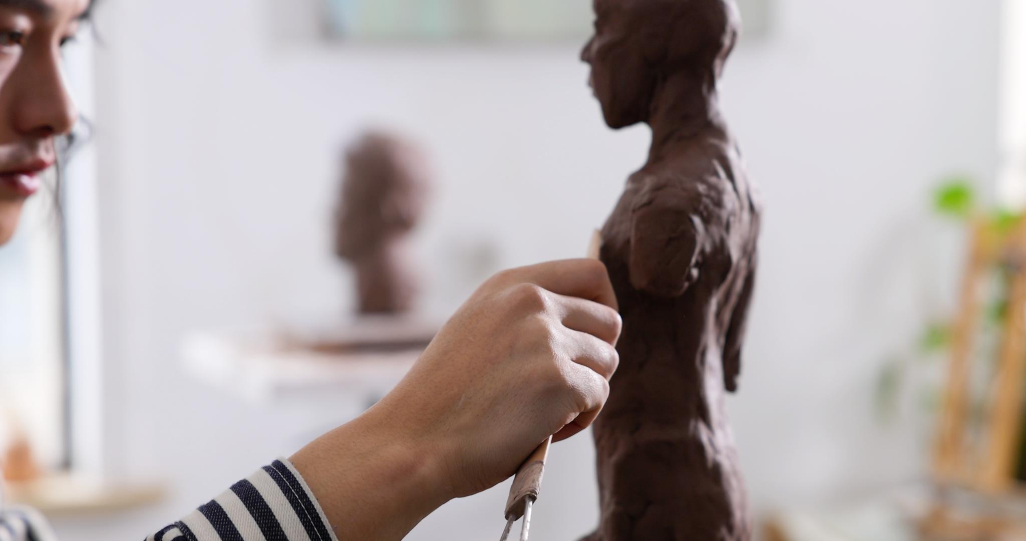 年轻男艺术家专注雕刻塑像特写视频的预览图