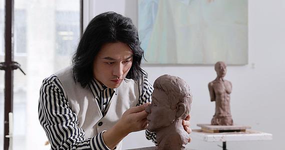 年轻男艺术家专注雕刻塑像视频的预览图
