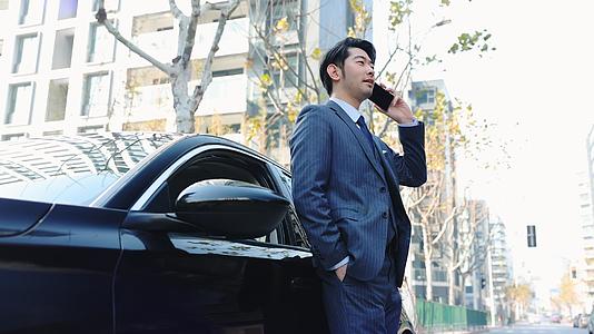 商务男青年靠着汽车接打电话视频的预览图