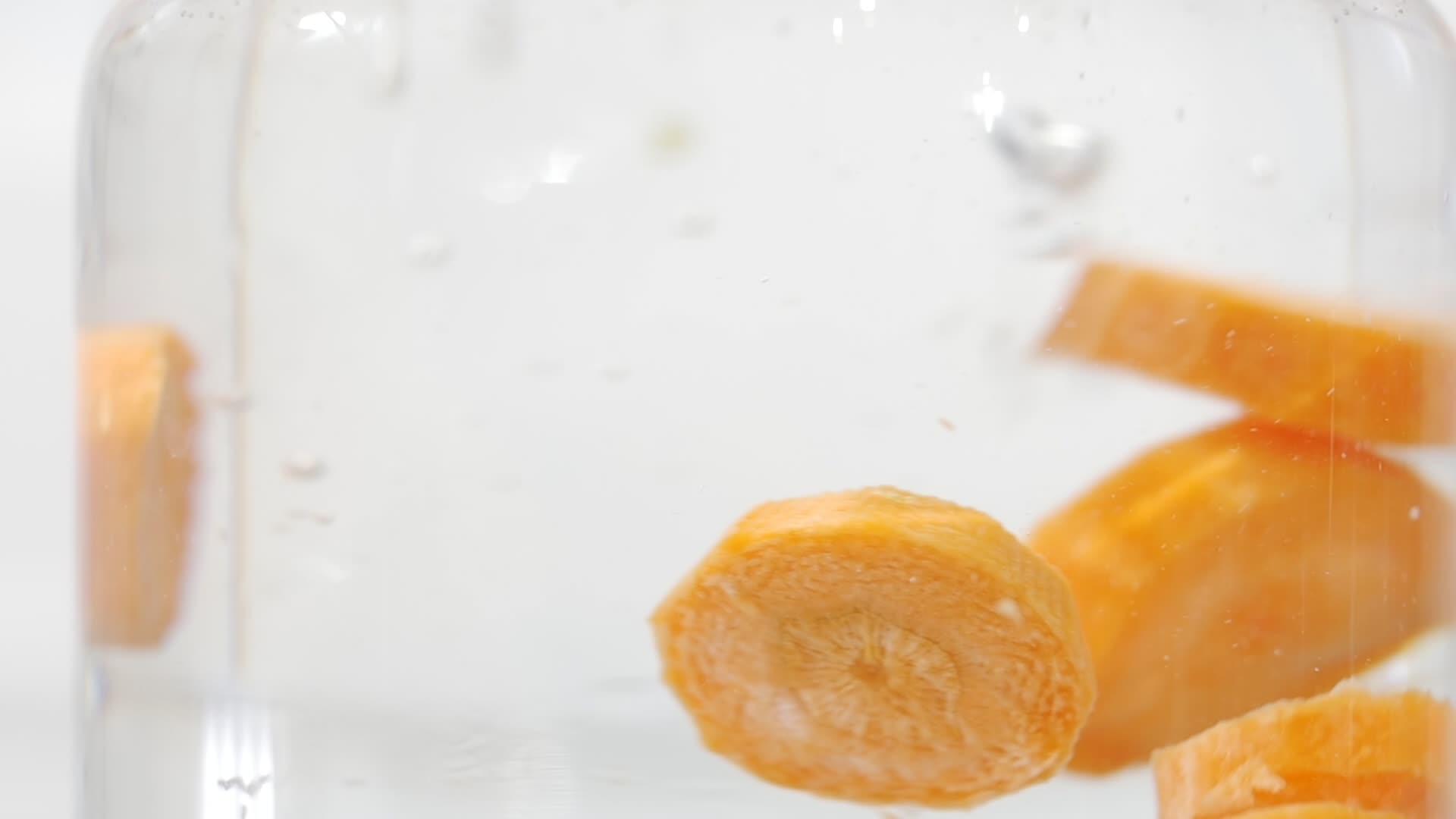 新鲜胡萝卜块的慢动作镜头溅水和玻璃中的气泡视频的预览图