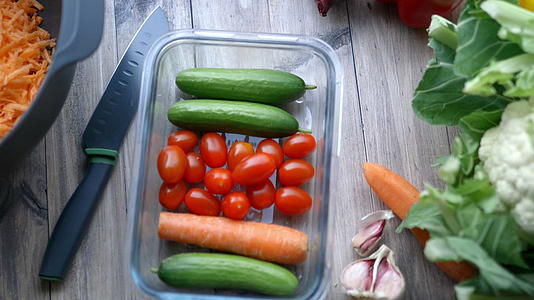 从装有蔬菜的塑料容器中采摘西红柿的女性视频的预览图