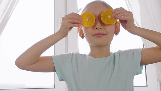 厨房窗窗口的背景前快乐的女孩拿着橙色的切片视频的预览图