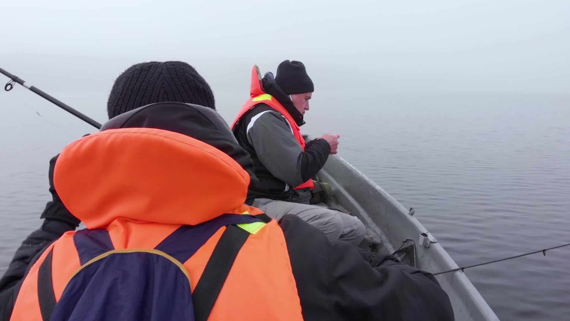 父亲和儿子在船上钓鱼在芬兰湖边的浓雾中钓鱼视频的预览图