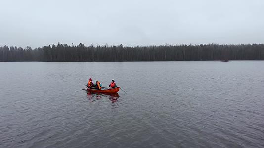 在芬兰秋天的湖上橙色的渔船和三个人在空中飞行视频的预览图