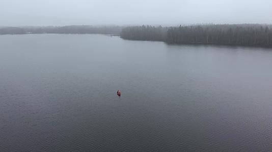 孤独的橙色船在芬兰空中角湖的浓雾中与壁草人在一起视频的预览图