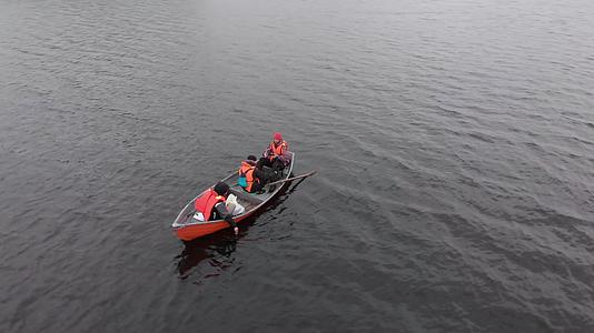 在芬兰空中螺旋湖的橙色船上三名身穿橙色救生衣的男子视频的预览图