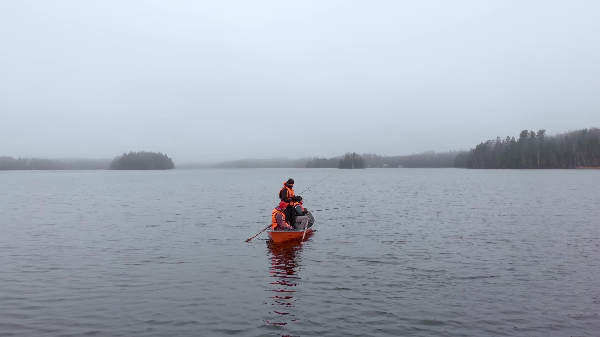 三个人在橙色的船上钓鱼在芬兰湖边的雾中静静地钓鱼视频的预览图