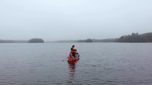 三个人在橙色的船上钓鱼在芬兰湖边的雾中静静地钓鱼视频的预览图