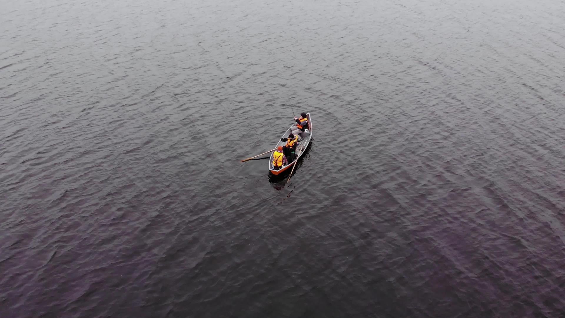 三名身穿橙色救生衣的男子在湖边的橙色船上捕鱼视频的预览图