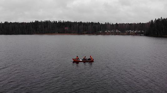 三名男子穿着橙色救生衣在芬兰湖上捕鱼视频的预览图