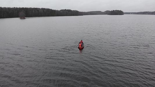 三名男子穿着橙色救生衣在芬兰航空湖上划船视频的预览图