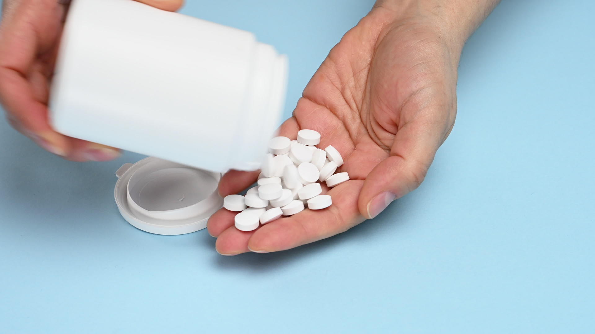 白色塑料罐上的白色圆球落在一名妇女的手上用来治疗疾病视频的预览图