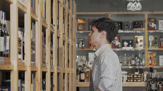 年轻的男性酿酒商在他们商店的货架上组织瓶子销售视频的预览图