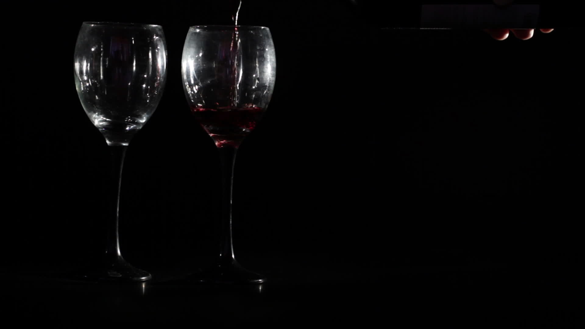 把红酒倒在两个黑色背景的杯子上视频的预览图