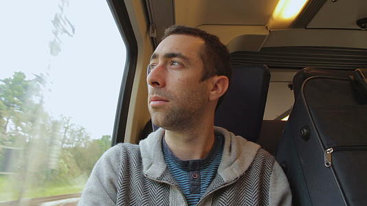 年轻人在火车上旅行看着窗外的窗户视频的预览图