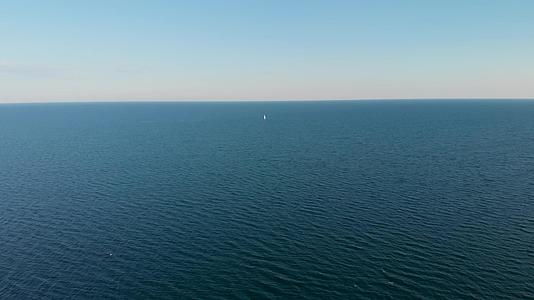 一艘孤独的白色游艇在蓝色无限海平面高空航行视频的预览图