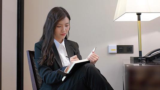 商务女性坐在椅子上看书记笔记视频的预览图