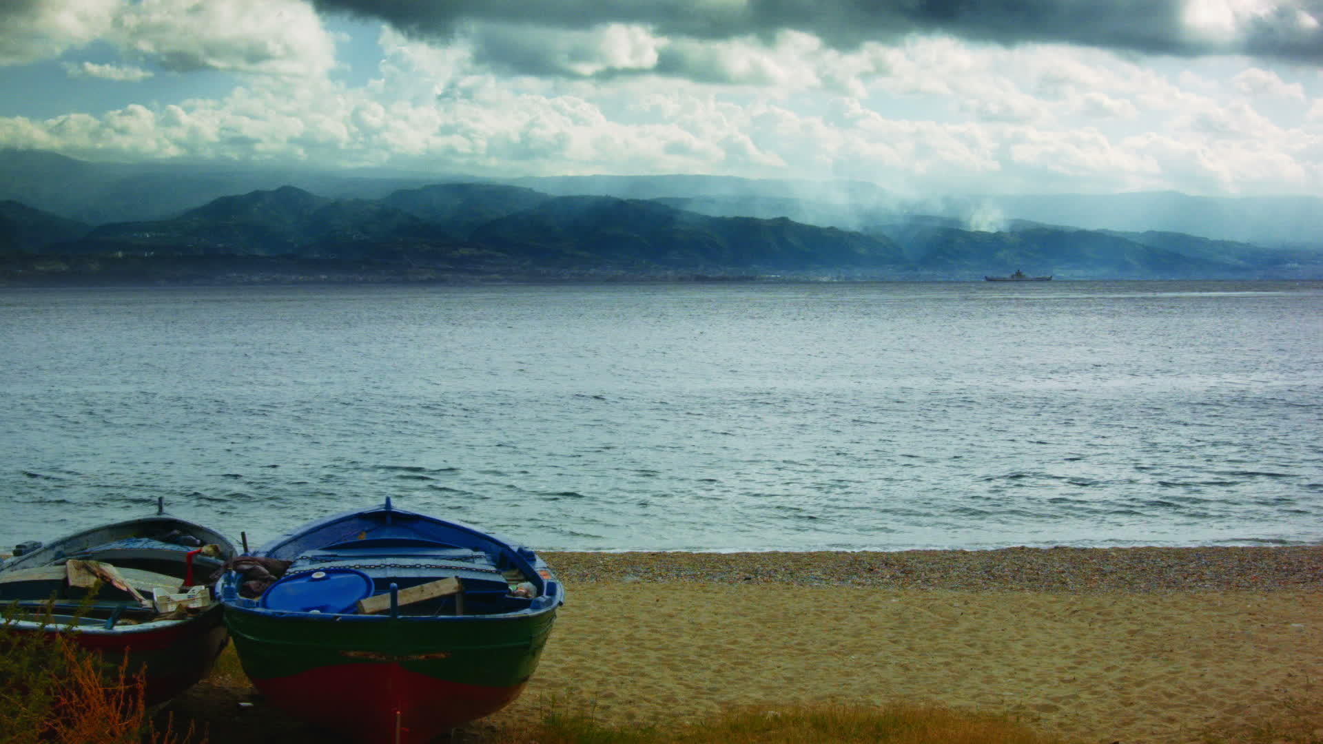 两条船在海滩上面对着平静的海面上面有强烈的云风视频的预览图