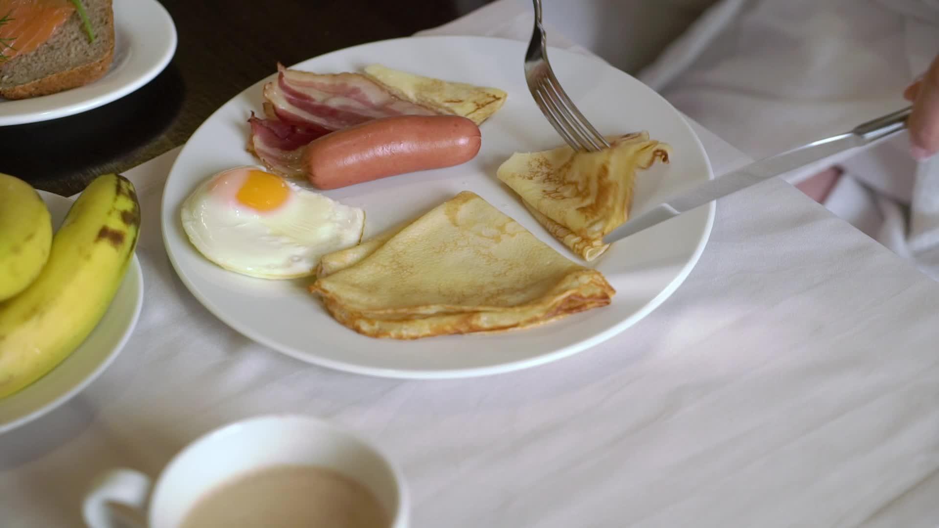 女人早上吃早餐盘子里有煎蛋和香肠视频的预览图
