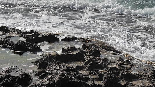岩石海岸上的绿藻在海风暴中流淌着柔软的碎水视频的预览图